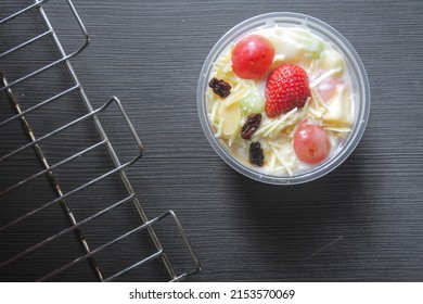 Fruit Salad with Yoghurt or salad buah yogurt on a wooden table. Fruit diet and holiday dessert