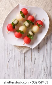 Fruit skewers with balls of watermelon, kiwi and melon on a plate. vertical top view - Shutterstock ID 302759453