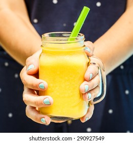 Fruit smoothie - healthy eating concept. Close up of  detox smoothie with mango. Woman hand holding  smoothies