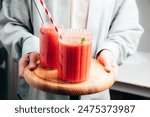 Fruit smoothie in transparent cups. Red strawberry smoothie in women