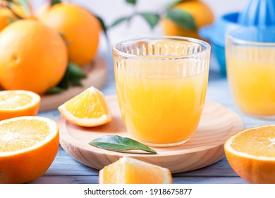 Fruit squeezer and ripe fresh oranges on blue wooden table top, fresh orange juice making, overhead