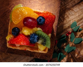 Fruit Tart On Wooden Table. Contains Strawberry, Mandarin, Blueberry And Kiwi.