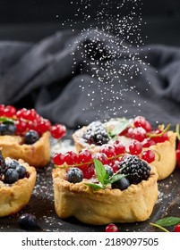 Fruit Tart With Red Currants Sprinkled With Powdered Sugar On A Black Table