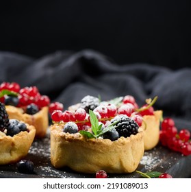 Fruit Tart With Red Currants Sprinkled With Powdered Sugar On A Black Table