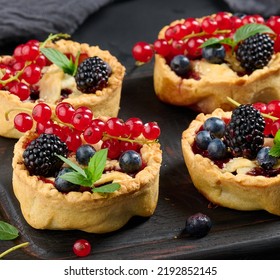 Fruit Tart With Red Currants Sprinkled With Powdered Sugar On A Black Table