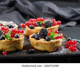 Fruit Tart With Red Currants Sprinkled With Powdered Sugar On A Black Table