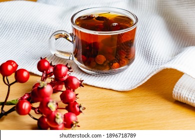 Fruit tea made from berries and rosehip fruits in a transparent glass mug. Hot drink like fresh compote on a white towel - Shutterstock ID 1896718789