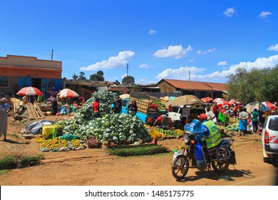 Fruit And Vegetable Market, Village Kenya, East Africa. February 2019, Local Kenyan People Buying And Selling Outdoors. Lots Of Cabbage, Parasols And Motorbike.  Travel By Road Through Kenya.