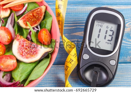 Fruit and vegetable salad, glucometer with result of measurement sugar level and tape measure, concept of diabetes, diet, slimming, healthy lifestyles and nutrition