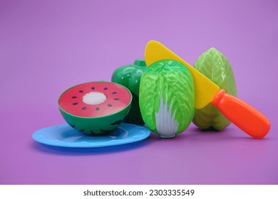 fruit and vegetable toys that can be split and then put back together. toy watermelon, cabbage, knife, bell pepper and star fruit isolated purple background. - Powered by Shutterstock