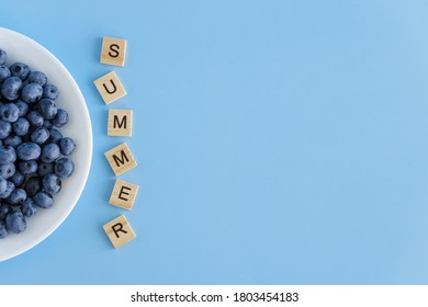 fruit and vegetable, vitamin, healthy food and drink, traditional medicine, gastronomy concept - layout of purple blueberry berries in white plate with inscription summer on blue background copy space - Shutterstock ID 1803454183
