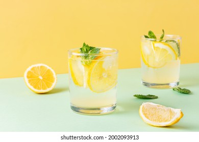 Fruit water with lemon and mint leaves on combined yellow and green background. Two glasses of cool carbonated cocktail with citrus. - Powered by Shutterstock