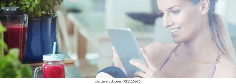 Fruitarian woman drinking red smoothie and searching for new recipes for vegan dishes using tablet - Powered by Shutterstock