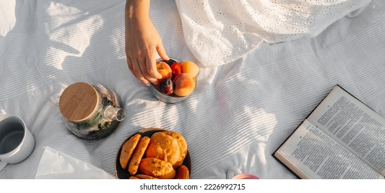 Fruits and book on white blanket, picnic outdoor. - Powered by Shutterstock