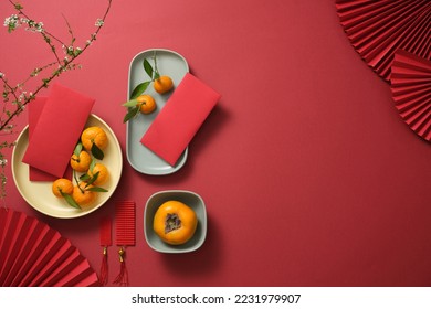 Fruits, lucky money, paper fan, and Lucky envelopes on a red background. Empty space for text. Chinese lunar new year. Top view