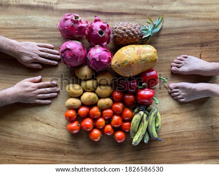 fruits on a wooden table top view with male hands and female feets