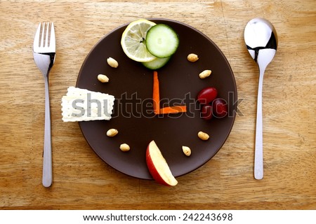 fruits, vegetables, nuts and crackers arranged on a plate like a clock