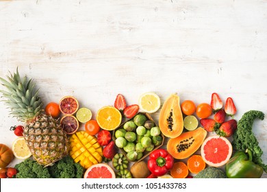 Fruits and vegetables rich in vitamin C, oranges mango grapefruit kiwi kale pepper pineapple lemon sprouts papaya broccoli, on wooden white table, top view, copy space, selective focus