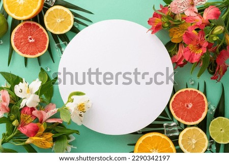 Fruity summer vibes concept. Top view flat lay of colorful alstroemeria flowers with ripe orange, grapefruit, lime, and lemon with palm leaves on pastel teal background with empty circle for promotion