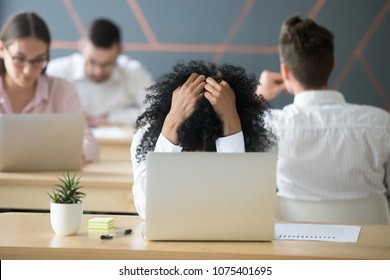 Frustrated african woman feeling despair panic shock sitting in shared office with laptop holding head in hands, upset stressed black employee or student tired of work, worried about online problem - Shutterstock ID 1075401695