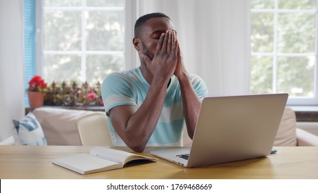 Frustrated afro-american guy sitting at his desk closing eyes massaging nose thinking on difficult task. Tired student studying from home, doing home work. E-learning - Shutterstock ID 1769468669