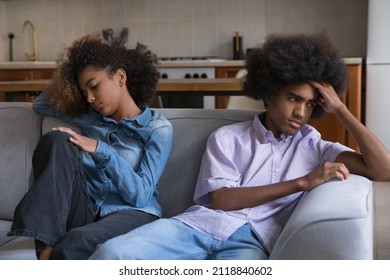 Frustrated angry African teen couple going through conflict, quarrel, ignore. Young African boyfriend and girlfriend sitting on couch separately keeping silence after row. Love relationships problems