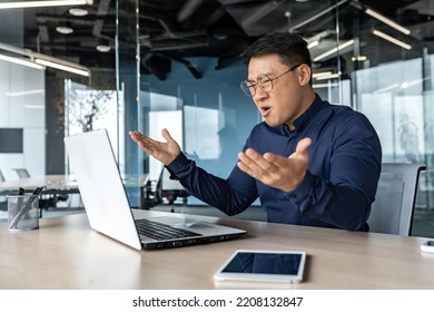 Frustrated And Angry Asian Boss Yelling At Laptop, Failure Man Working Inside Twisted Office Building At Desk