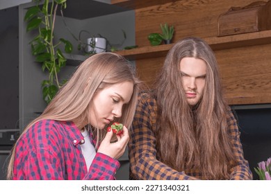 Frustrated angry man with long hair in kitchen and sad young wom