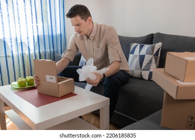 Frustrated Annoyed Man, Client, Shopper Opening Box, Looking At Damaged Goods. Delivery Service Error, Courier Mistake Concept. Upset Dissatisfied Customer Receiving Wrong Parcel From Internet Store.