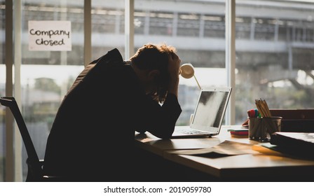 Frustrated and anxious Caucasian businessman sitting and holding hands on head. He got unemployed from the company closed. Financial problem, bankruptcy, and layoff concept.
