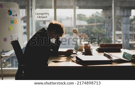 Frustrated and anxious Caucasian businessman sitting and holding hands on head. He got unemployed from the company closed. Financial problem, bankruptcy, and layoff concept.