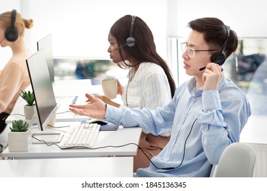 Frustrated Asian Helpdesk Operator Dealing With Client's Problem At Modern Call Centre. Technical Support Agent Consulting Customer Online, Providing Telecommunications Services