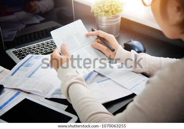 Frustrated Asian woman holding and looking at\
saving account book, bill and calculating her monthly expenses and\
Debts at house. Bankrupt Female having problem income, budget,\
payment. Economic\
crisis