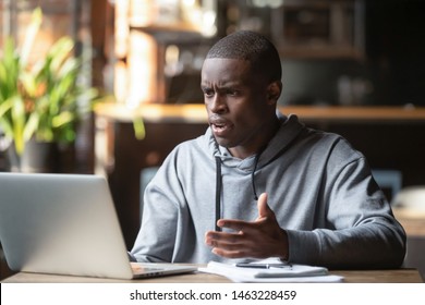 Frustrated black male student work at laptop get mad having device software operational problems, angry african American guy man feel confused with slow internet connection on computer or virus attack