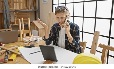 Frustrated blonde woman on a phone call in a cluttered woodworking workshop - Powered by Shutterstock