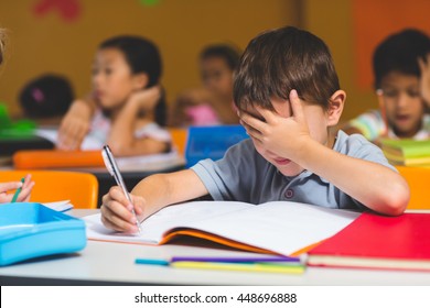 Frustrated Boy With Hand Covering Face In Classroom