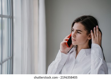 Frustrated brunette hispanic young woman talking by phone with husband, in troubles. Pretty caucasian girl at home using cell phone looking hopelessly at window. Upset housewife. Mockup sad girl. - Shutterstock ID 2196358405
