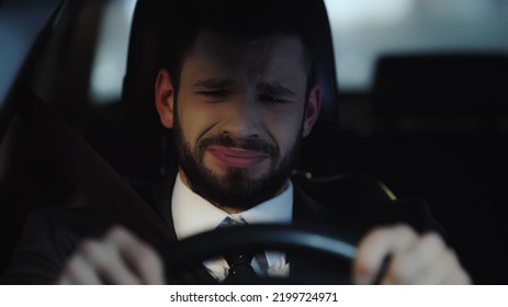 Frustrated Businessman Crying While Driving Car At Night