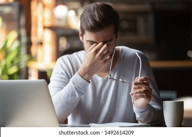 Frustrated businessman holding glasses feel eye strain, stressed overworked man massage nose bridge feel headache having bad blurry vision weak sight macular problem suffer from computer work syndrome