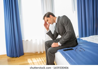 Frustrated Businessman Sitting On The Hotel Bed Holding His Hand On Head