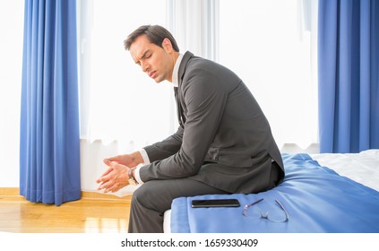 Frustrated Businessman Sitting On The Hotel Bed Holding His Hand On Head