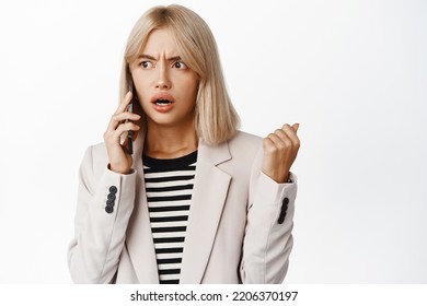 Frustrated Businesswoman Over Phone Call. Young Corporate Woman Talking On Smartphone With Confused Face Expression, White Background.