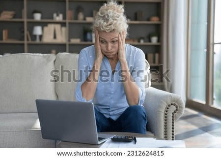 Frustrated concerned mature elder woman worried about finance problems, overspending, money loss, too high price, bankruptcy risk, looking at laptop, calculator in shock