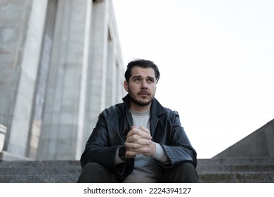 frustrated depressed man looking into space while sitting on steps outside