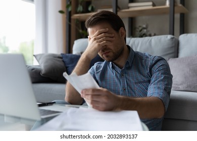 Frustrated desperate millennial man checking bills for payments, holding receipts, getting upset about overspending, too high mortgage, insurance fees. Homeowner analyzing costs, expenses, budget - Shutterstock ID 2032893137