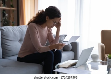 Frustrated desperate young woman in eyeglasses touching forehead, looking through banking credit termination, having financial problems, reading refusal document, feeling depressed alone at home. - Shutterstock ID 1714287598