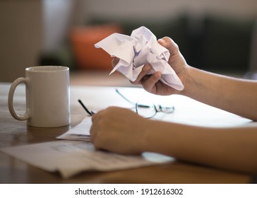 A frustrated discouraged woman crumpling a paper at work on her desk. 