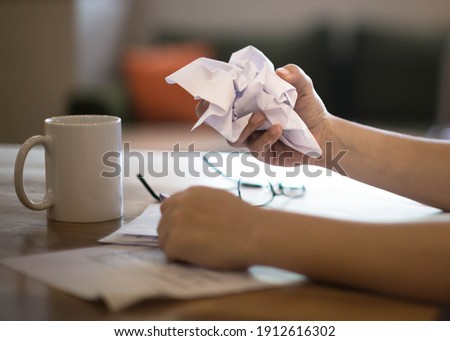 A frustrated discouraged woman crumpling a paper at work on her desk. 