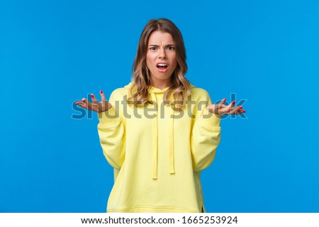 Frustrated and displeased confused young blond girl shrugging, looking at camera with disagreement and bothered expression, hear nonsense, have argument cant understand what happening