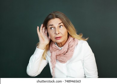 Frustrated Elderly Woman Suffering From Deafness, Trying Hard To Hear Something. Curious Senior Female Eavesdropping, Holding Hand At Her Ear And Listening Attentivel. Difficulty In Hearing